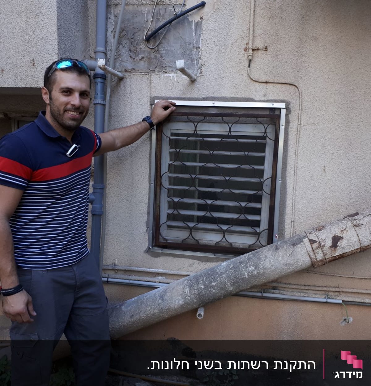 אדם ליד חלון עם מסגרת אלומיניום על קיר חיצוני